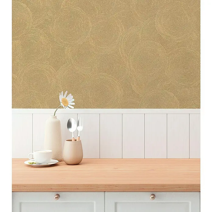 A.S. Création Hygge 3 Vliestapete Kreise - Braun-Gelb, Grafisch, 10,05 x 0,53 m - Ein Küchentisch mit einem weißen Schrank, Geschirr, einer Blume und einer strukturierten Tapete mit Kreismuster im Hintergrund.