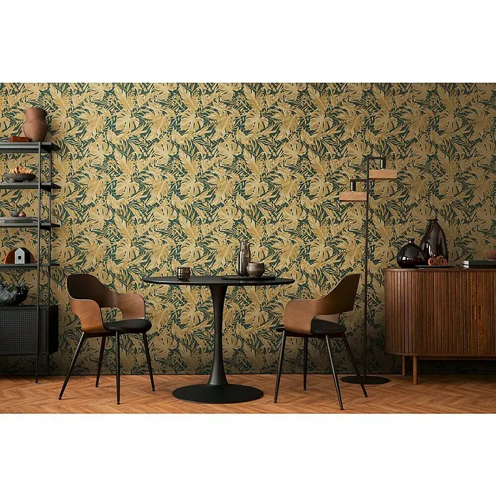 A.S. Création Cosmoliving by Cosmopolitan Vliestapete Blätter - Grün-Gold, Floral, 10,05 x 0,53 m - Moderner Essbereich mit einem eleganten runden Tisch, umgeben von stilvollen Holzstühlen und ergänzt durch ein dekoratives Bücherregal.