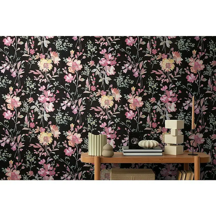 A.S. Création Cosmoliving by Cosmopolitan Vliestapete Blüten - Schwarz-Pink-Grün, Floral, 10,05 x 0,53 m - Elegante Nahaufnahme einer Wand mit schwarzer Blumentapete, die eine Konsole mit Deko-Artikeln wie Kerzen und Vasen ziert.