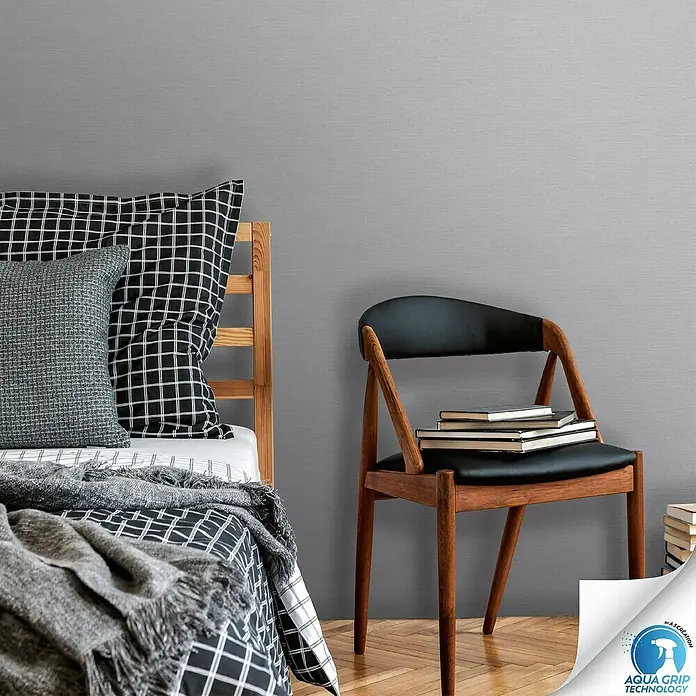 A.S. Création Designdrop Vliestapete - Hellgrau, Uni, 10,05 x 0,53 m - Graue Tapete im Schlafzimmer mit Bett und Stuhl. Die Tapete hat eine feine Textur und verleiht dem Raum eine moderne Note.