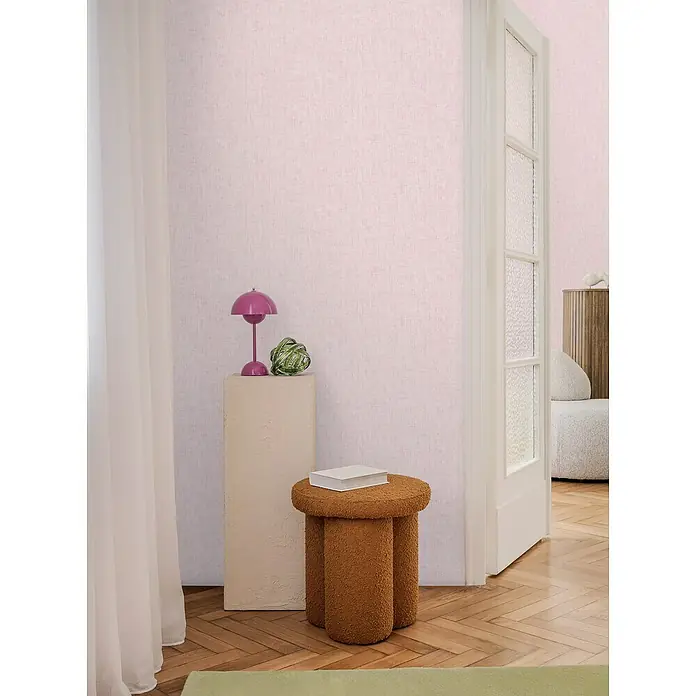 A.S. Création Cosmoliving by Cosmopolitan Vliestapete - Altrosa, Uni, 10,05 x 0,53 m - Innenaufnahme eines stilvollen Raumes mit einem auffälligen, beigefarbenen Hocker mit drei Beinen und einem Buch darauf.