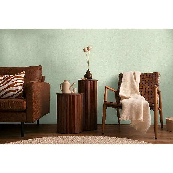 A.S. Création Cosmoliving by Cosmopolitan Vliestapete - Hellgrün, Uni, 10,05 x 0,53 m - Gemütliches Wohnzimmer mit braunem Sofa, Holzhocker und Akzenten in Naturtönen. Einladendes Ambiente für entspannte Stunden.