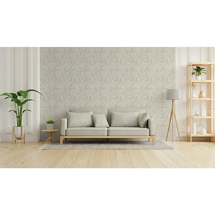 A.S. Création Hygge 3 Vliestapete Blätter - Beige-Creme-Grau, Floral, 10,05 x 0,53 m - Wohnzimmer mit beigem Sofa, Stehlampe und Bücherregal. Das Sofa ist der zentrale Punkt und lädt zum Verweilen ein, während das Bücherregal zusätzlichen Stauraum bietet.