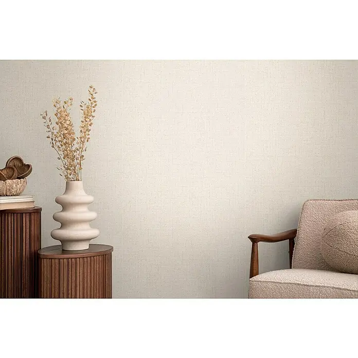 A.S. Création Cosmoliving by Cosmopolitan Vliestapete - Helles Cremebeige, Uni, 10,05 x 0,53 m - Einrichtungsszene mit beigem Sessel, Holzschrank und einer dekorativen Vase mit getrockneten Blumen. Die Texturtapete rundet das Bild ab.