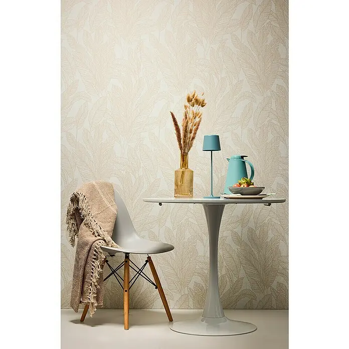 A.S. Création Cosmoliving by Cosmopolitan Vliestapete Blättergrafik - Beige-Creme-Braun, Floral, 10,05 x 0,53 m - Stilvolle Tischszene mit blauer Thermoskanne und dekorativer Vase auf einem modernen Tisch mit Tulpenfuß vor floral gemusterter Tapete.