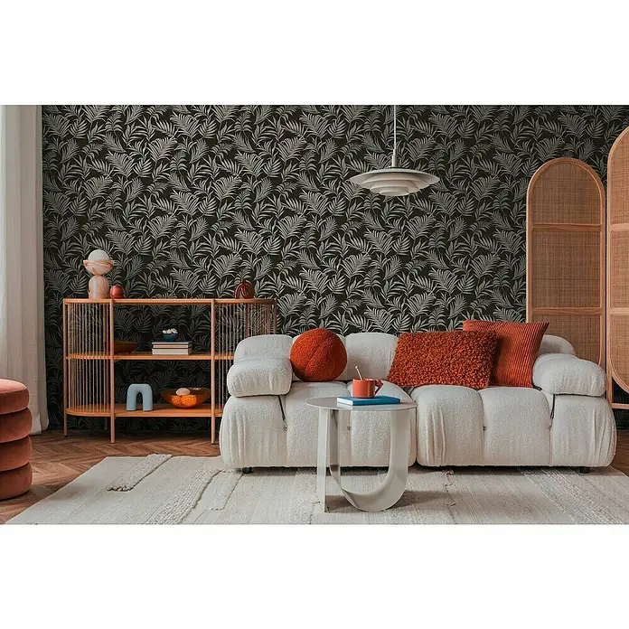 A.S. Création Cosmoliving by Cosmopolitan Vliestapete Ranken - Schwarz-Grau-Blau, Floral, 10,05 x 0,53 m - Wohnzimmer mit modernem weißen Sofa, Beistelltisch und einem Regal mit Dekorationsgegenständen vor einer gemusterten Tapete.