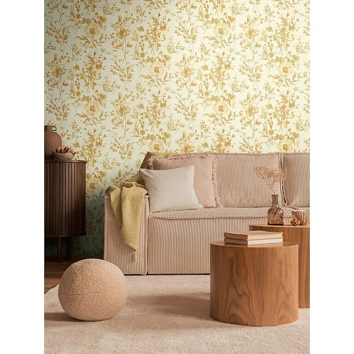 A.S. Création Cosmoliving by Cosmopolitan Vliestapete Blüten - Gold-Weiß-Beige, Floral, 10,05 x 0,53 m - Einladendes Wohnzimmer mit stilvollem Cord-Sofa, floraler Tapete und Holztischen, die eine warme und gemütliche Atmosphäre schaffen.
