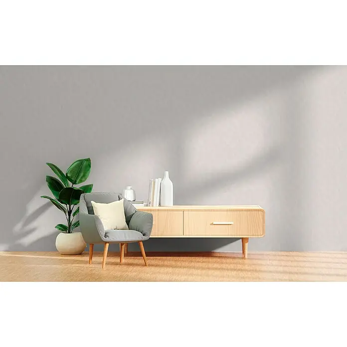 A.S. Création Hygge 3 Vliestapete Kreise - Creme-Weiß, Grafisch, 10,05 x 0,53 m - Wohnzimmer mit einem hellen Holzschrank, einem grauen Sessel und einer Zimmerpflanze vor einer grauen Wand.