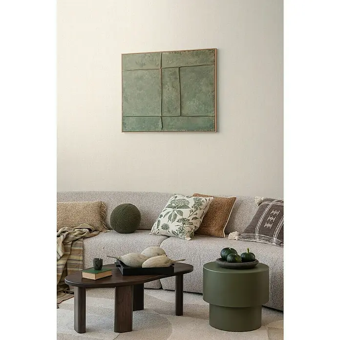 A.S. Création Cosmoliving by Cosmopolitan Vliestapete - Hell-Beige, Uni, 10,05 x 0,53 m - Ein Wohnzimmer mit einem grauen Sofa, einem Couchtisch und einem grünen Beistelltisch. An der Wand hängt ein grünes Kunstwerk.