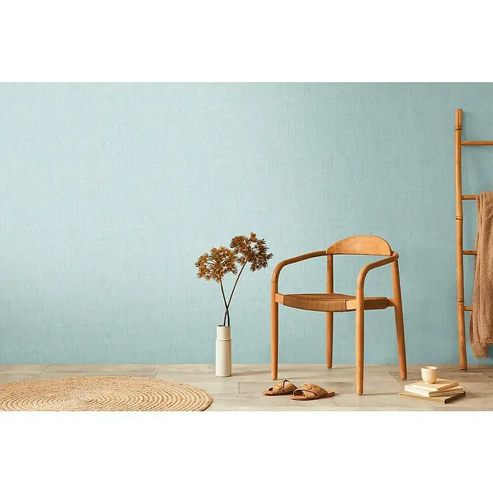 A.S. Création Cosmoliving by Cosmopolitan Vliestapete - Helles Blau, Uni, 10,05 x 0,53 m - Einladende Szene mit einem eleganten Holzstuhl, dekorativen Elementen und einem Hauch von Gemütlichkeit.