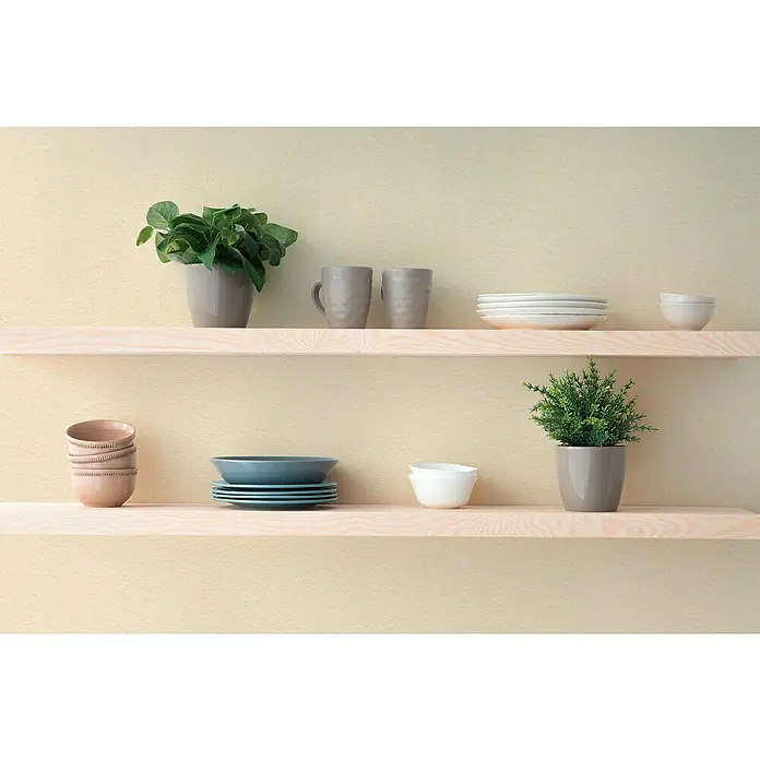 A.S. Création Hygge 3 Vliestapete - Beigecreme, Uni, 10,05 x 0,53 m - Ein Foto von zwei Holzregalen an einer beigen Wand mit verschiedenen Schalen, Tellern, Tassen und zwei Pflanzen in Töpfen.