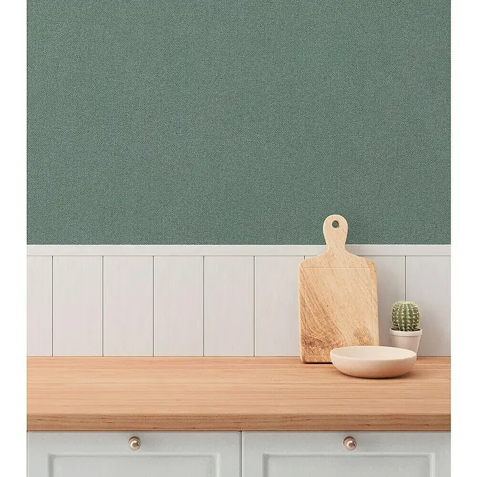 A.S. Création Hygge 3 Vliestapete - Grün II, Uni, 10,05 x 0,53 m - Detailaufnahme einer hölzernen Küchentheke mit Schneidebrett, Schale und Kaktus, die eine warme und einladende Atmosphäre vermitteln.