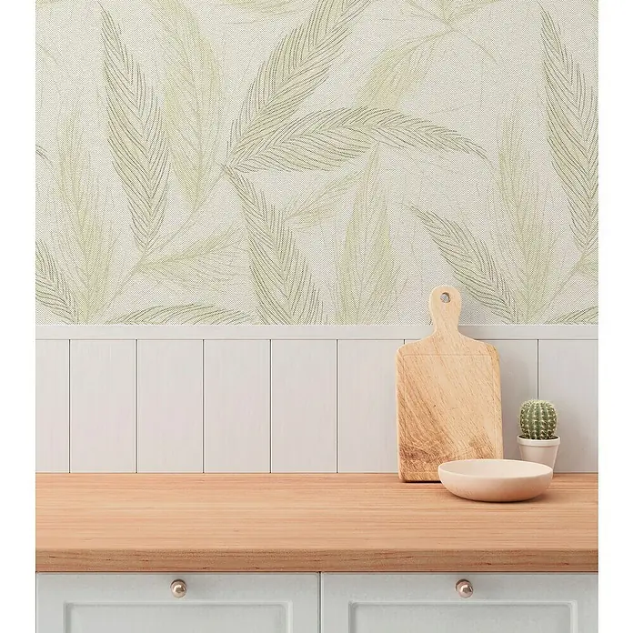 A.S. Création Hygge 3 Vliestapete Blätter - Creme-Grün-Silber, Floral, 10,05 x 0,53 m - Hölzernes Schneidebrett und Schale auf einer Küchentheke vor einer Wand mit Blättertapete.