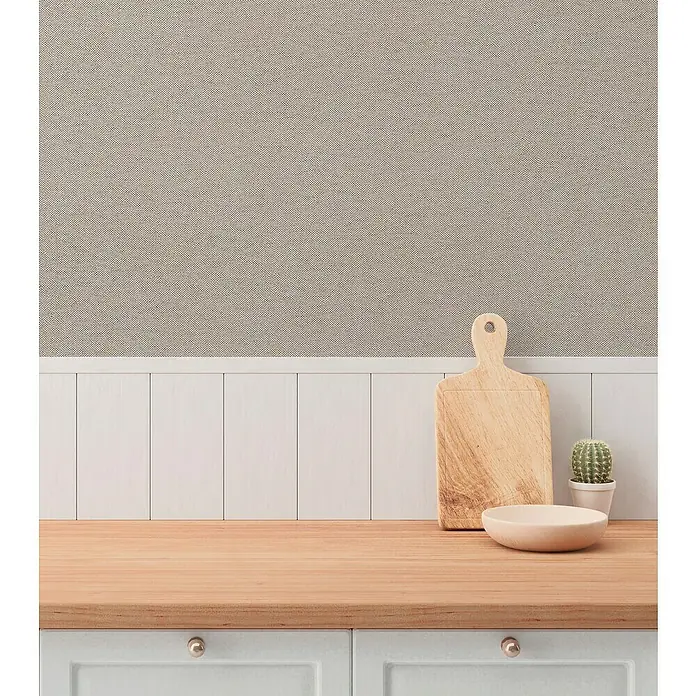 A.S. Création Hygge 3 Vliestapete - Graubraun, Uni, 10,05 x 0,53 m - Hölzernes Schneidebrett, Schale und Kaktus auf einer Küchentheke mit hellgrauen Schrankfronten und goldfarbenen Knöpfen.