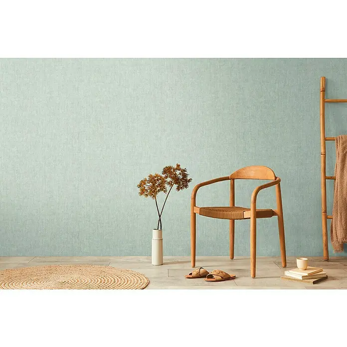A.S. Création Cosmoliving by Cosmopolitan Vliestapete - Türkisgrün, Uni, 10,05 x 0,53 m - Einladendes Interieur mit einem stilvollen Holzstuhl, einer Leiter mit Handtuch und einem dekorativen Teppich, das ein gemütliches Ambiente schafft.