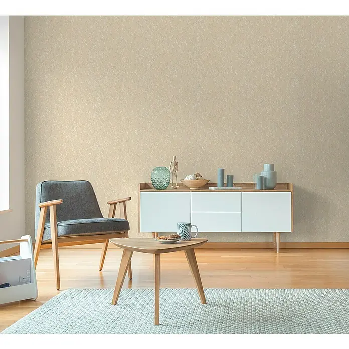 A.S. Création Hygge 3 Vliestapete Ranken - Beige-Gelb-Creme, Floral, 10,05 x 0,53 m - Wohnzimmer mit bequemen Sessel, Holztisch, Teppich und Sideboard mit Dekorationen, die eine gemütliche Atmosphäre schaffen.