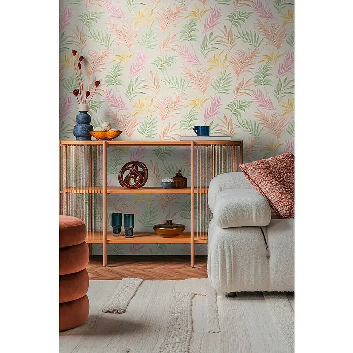 A.S. Création Cosmoliving by Cosmopolitan Vliestapete Ranken - Weiß-Grün-Rosa, Floral, 10,05 x 0,53 m - Wohnzimmer-Interieur mit einem modernen Regal vor einer Tapete mit Blättermuster. Ein weißes Sofa und ein Pouf ergänzen das Ensemble.