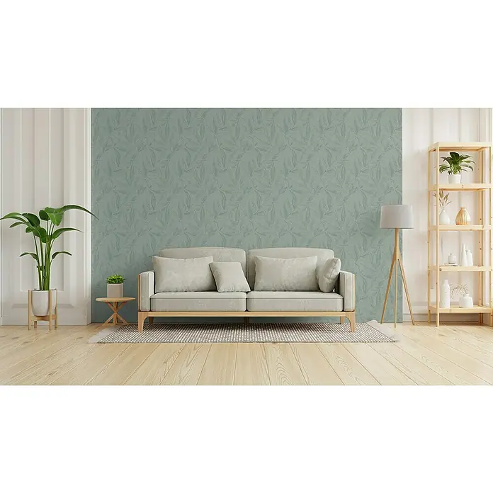 A.S. Création Hygge 3 Vliestapete Blätter - Grün-Metalllic, Floral, 10,05 x 0,53 m - Gemütliches Wohnzimmer mit modernem Sofa, Zimmerpflanze und Bücherregal. Die grüne Wand mit Blattmuster sorgt für eine entspannende Atmosphäre.