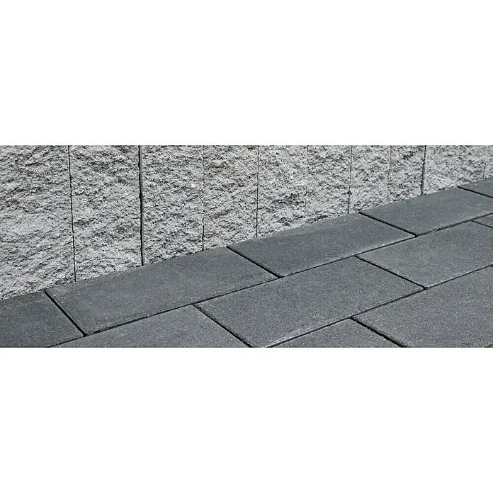 Christoph Pflasterstein - Kristall-Anthrazit, 40 x 20 x 6 cm, Rechteck - Pflastersteine in Grau, verlegt in einem regelmäßigen Muster neben einer grauen Steinmauer. Ideal für Gartenwege und Terrassen.