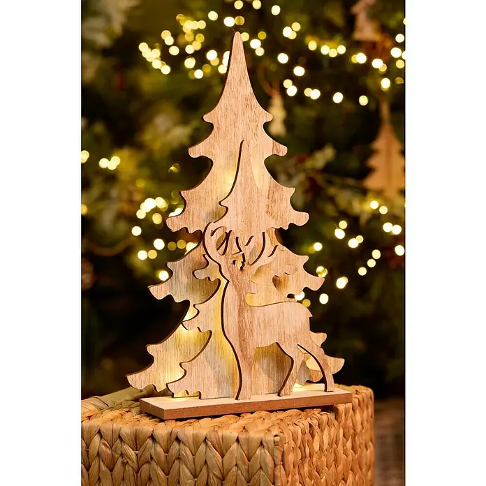 Cesta de fibras naturales - L x An x Al: 38 x 28 x 20 cm, Natural - Primer plano de una decoración de árbol de Navidad de madera con un reno recortado, sobre una cesta de mimbre frente a luces borrosas.