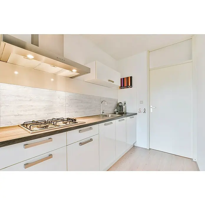 Bariperfil Protector de pared de cocina Backsplash - White oak, 60 x 98 cm, Aluminio - Un diseño de cocina luminoso con una campana extractora moderna sobre la placa de cocina, armarios blancos y una encimera oscura.