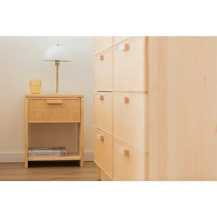 Astigarraga Aura Conjunto de muebles - 5 pzs., Madera maciza y rafia, Natural - Primer plano de una mesita de noche de madera clara con un cajón de ratán, rematada con una lámpara y un vaso.