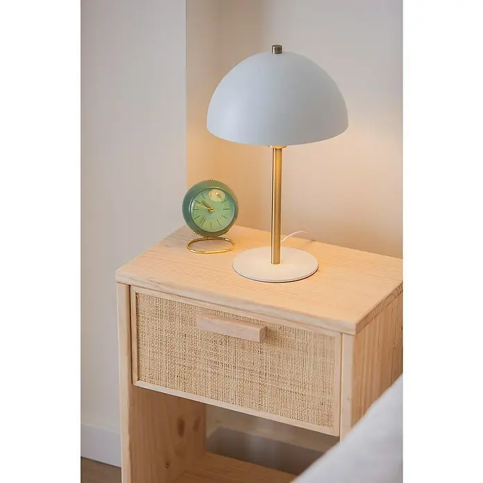 Astigarraga Aura Conjunto de muebles - 5 pzs., Madera maciza y rafia, Natural - Primer plano de una lámpara de noche con pantalla de cúpula y base de latón, junto a un reloj verde vintage sobre un armario de madera.