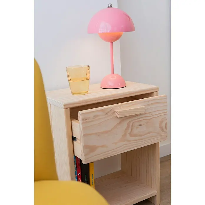Astigarraga Vita Conjunto de muebles - Natural, 4 pzs. - Mesita de noche de madera de pino con un cajón y una lámpara rosa encima, junto a un sillón amarillo.