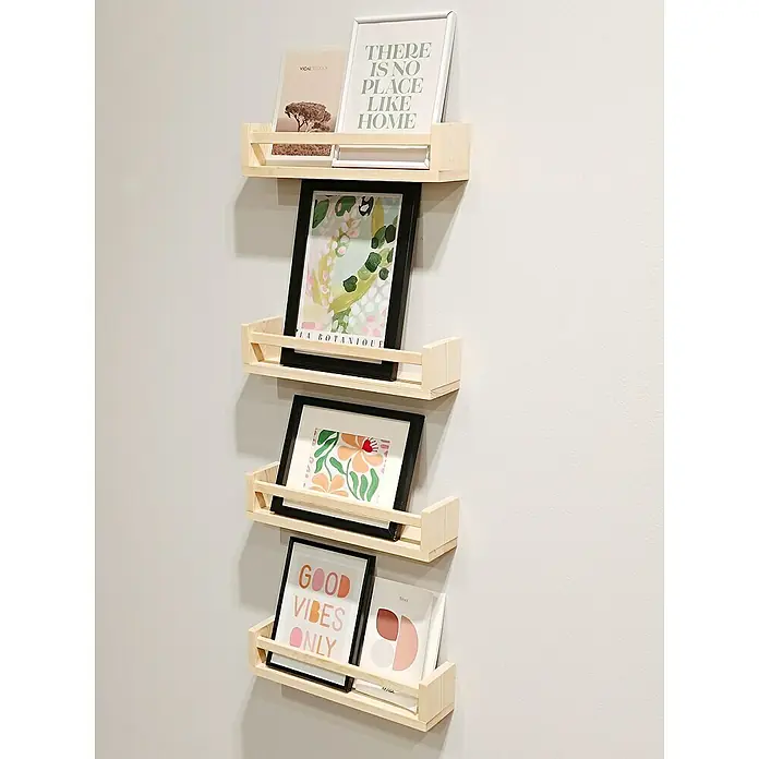 Astigarraga Especiero - L x An x Al: 15 x 40 x 15 cm, Madera, Natural - Un primer plano de cuatro estantes de pared de madera montados uno encima del otro en una pared, que muestran marcos de fotos y libros.