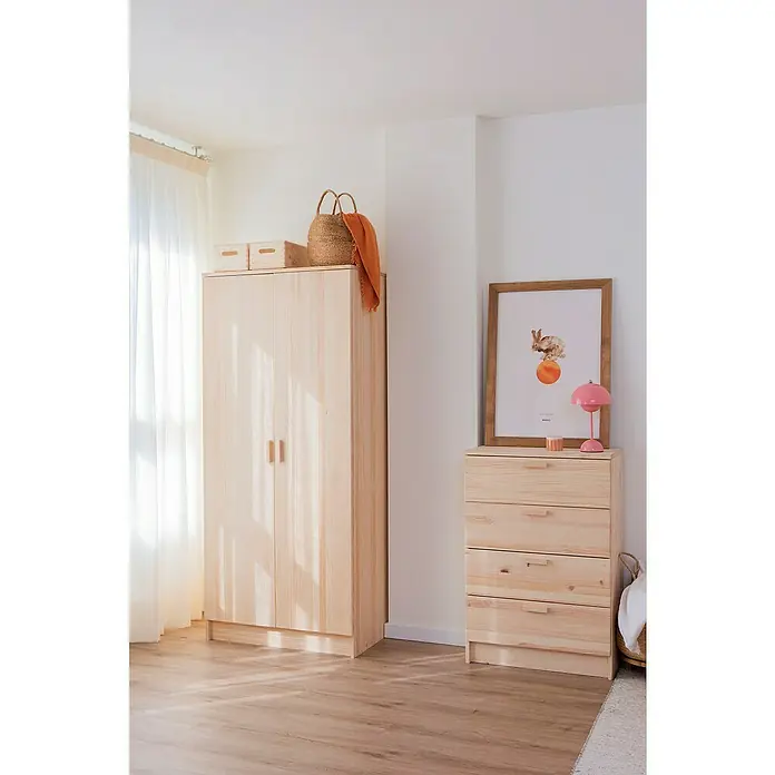 Astigarraga Vita Conjunto de muebles - Natural, 4 pzs. - Dormitorio luminoso con un armario y una cómoda de madera clara, decorados con un cuadro, una lámpara y cestas, creando un ambiente cálido y natural.