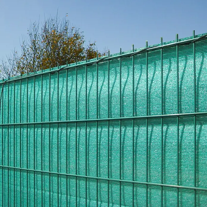 Peddy Shield Sichtschutz - HDPE Gewebe, Grün, 5 x 1,6 m - Nahaufnahme eines grünen Drahtzauns mit Sichtschutznetz, der Privatsphäre und Sicherheit bietet.\n