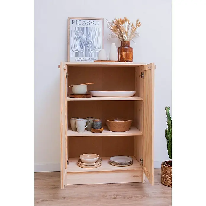 Astigarraga Aura Conjunto de muebles - 2 pzs., Madera maciza y rafia, Natural - Un armario de madera abierto con tres estantes, lleno de vajilla y decoración, contra una pared blanca. Una obra de arte decorativa descansa encima.
