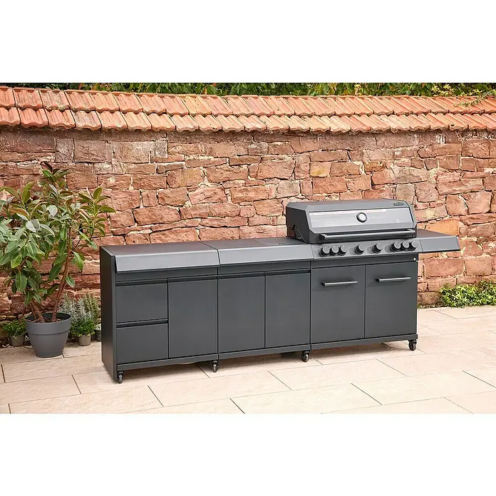 Kingstone Outdoorküchen-Modul Cliff Big Basic - Schwarz, B x T x H: 82 x 55,5 x 91 cm - Ein grauer Outdoor-Küchengrill mit Schränken und Arbeitsflächen vor einer Steinmauer. Das Küchengerät ist mit Rollen ausgestattet.