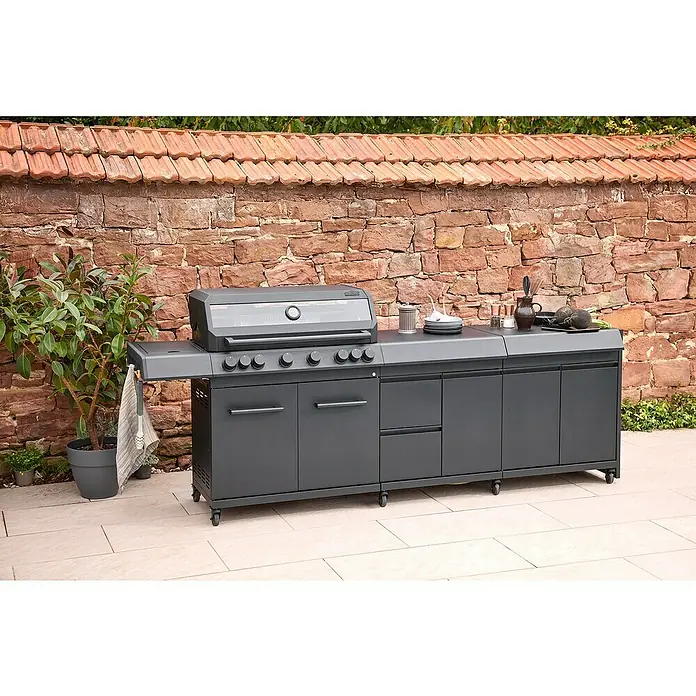 Kingstone Outdoorküchen-Modul Cliff Big Basic - Schwarz, B x T x H: 82 x 55,5 x 91 cm - Eine moderne graue Outdoor-Küche mit Grill, Arbeitsfläche und Stauraum vor einer Steinmauer.