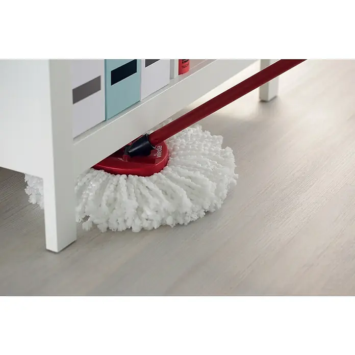 Vileda Set de limpieza Turbo smart - Otros, Rojo/Gris - Primer plano de una fregona Vileda bajo un estante blanco, limpiando un suelo de madera clara. Perfecto para el mantenimiento.
