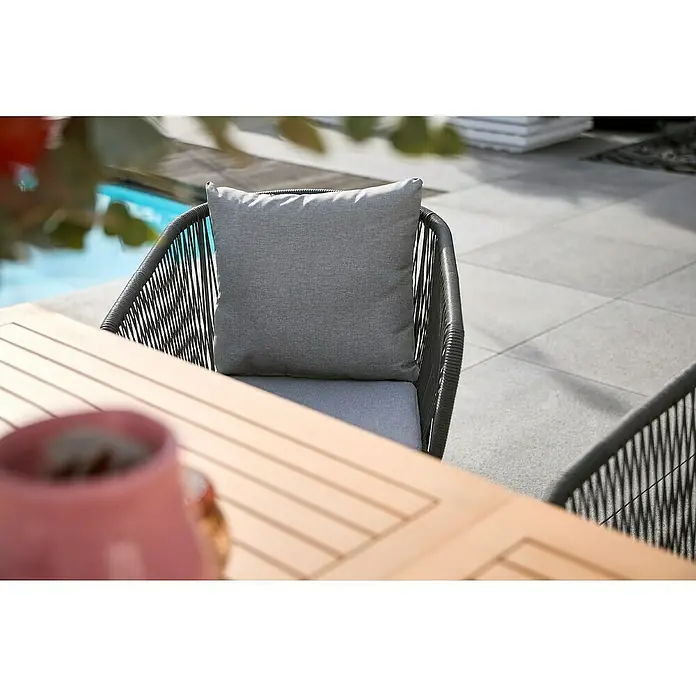 Sunfun Maja Gartensessel - Kunststofffaser-Strings, Grau, B x T x H: 62 x 62 x 78 cm - Nahaufnahme eines Outdoor-Stuhls mit grauem Kissen und Tisch. Ideal für entspannte Stunden im Freien.