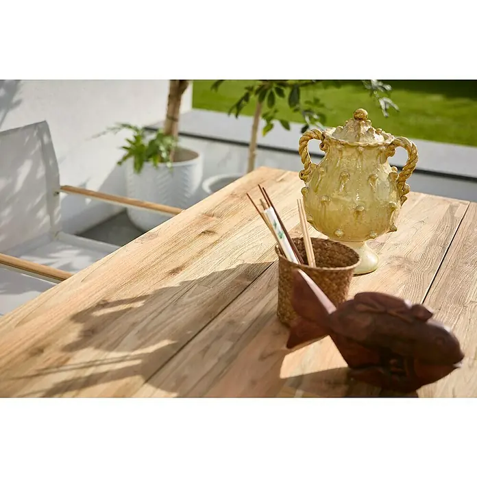 Sunfun Garten-Tischplatte - L x B: 180 x 90 cm, Teak, Schweizer Kante - Eine Nahaufnahme eines dekorierten Holztisches mit Geschirr, einem Gefäß, Essstäbchen und einer Holzfischfigur.