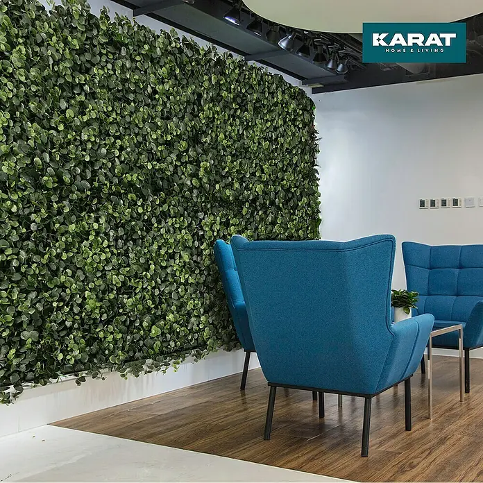 Floordirekt Kunstpflanze Pflanzenwand Eucalyptus 50 x 50 cm - Blütenfarbe: Grün, Kunststoff - Eine Wand mit dekorativen Pflanzenpaneelen von Karat Home & Living, die einen frischen und natürlichen Look in den Raum bringen. Blaue Sessel ergänzen das Design.