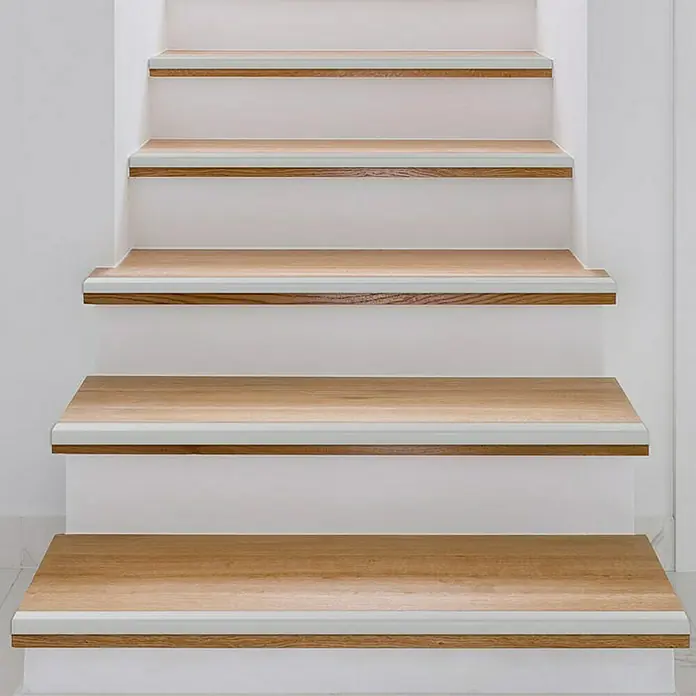 Floordirekt Treppenkantenprofil Integral Vorgebohrt 90 x 3 x 2 cm Silber - Aluminium, Silber - Elegante Treppe mit hellen Holzstufen und weißen Setzstufen, die ein modernes und stilvolles Designelement im Raum darstellt.