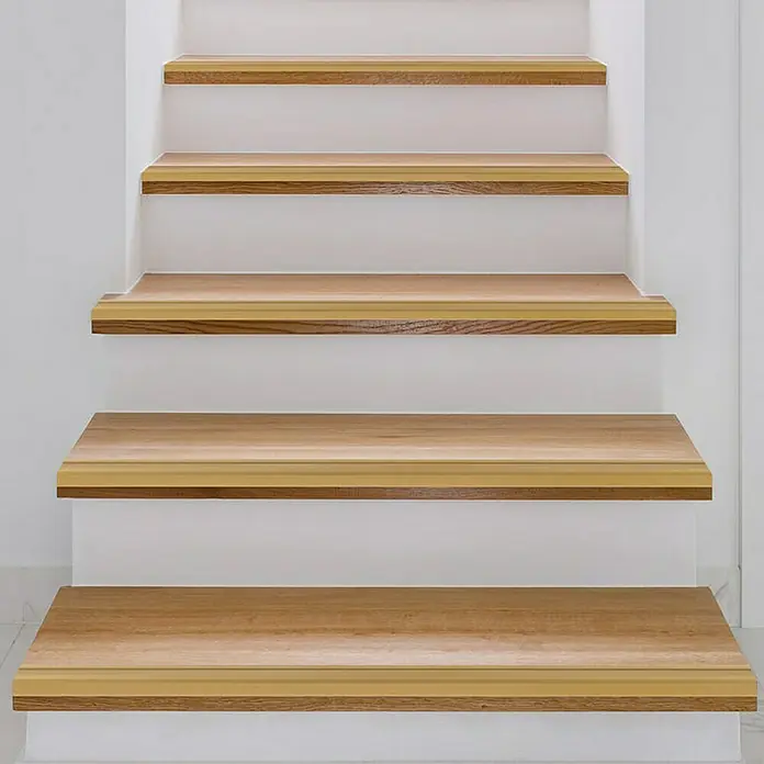 Floordirekt Treppenkantenprofil Glory 100 cm Gold - Aluminium, Gold, 100 x 1,7 cm, Eloxiert - Nahaufnahme einer Treppe mit Holzstufen und weißen Setzstufen, die ein modernes und sauberes Design zeigt.