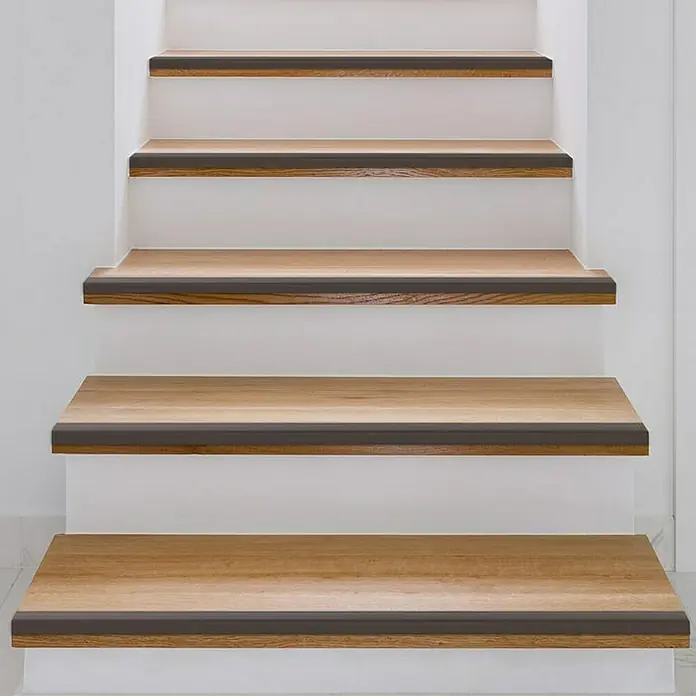 Floordirekt Treppenkantenprofil Integral 90 x 3 x 2 cm Bronze - Aluminium, Bronze - Nahaufnahme von Holztreppen mit dunklen Kantenprofilen, die für Sicherheit und einen modernen Look sorgen. Ideal für jedes Zuhause.