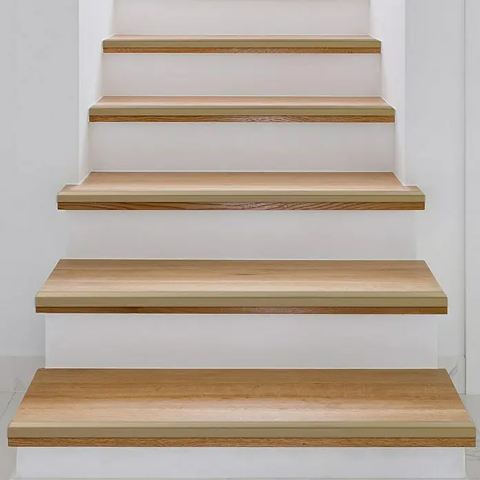 Floordirekt Treppenkantenprofil Integral 90 x 3 x 3,5 cm Gold - Aluminium, Gold, 90 x 3,5 cm - Nahaufnahme von hellen Holztreppenstufen mit weißen Setzstufen, die ein modernes und minimalistisches Design zeigen.