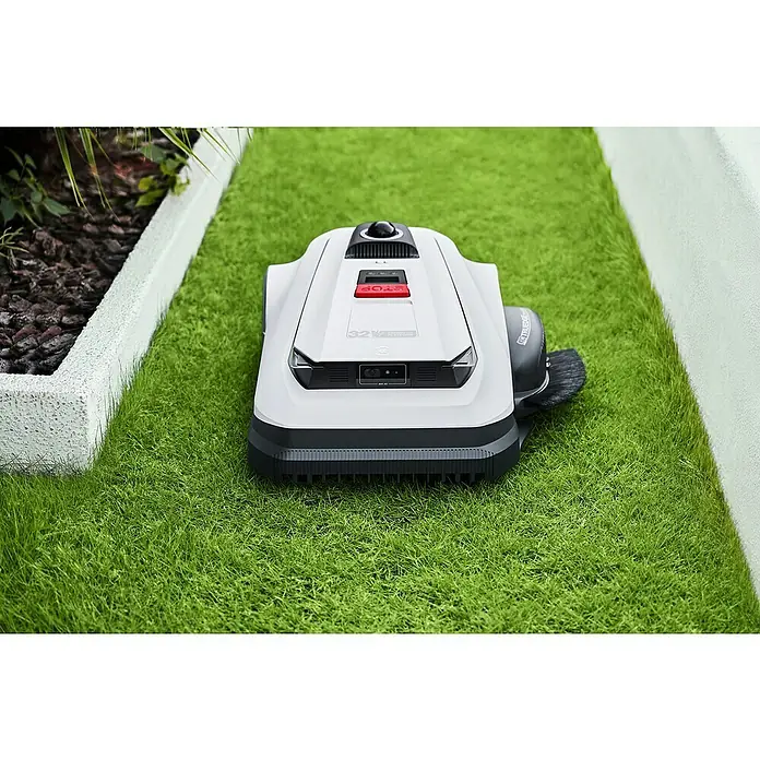 Ecovacs Goat Mähroboter A3000 LiDAR Pro - 3.000 m², Schnittbreite: 33 cm, Laser-gestützte Navigation, LiDAR - Nahaufnahme eines weißen Staubsaugerroboters auf einem Rasenstück, der sich für die Rasenpflege eignet.