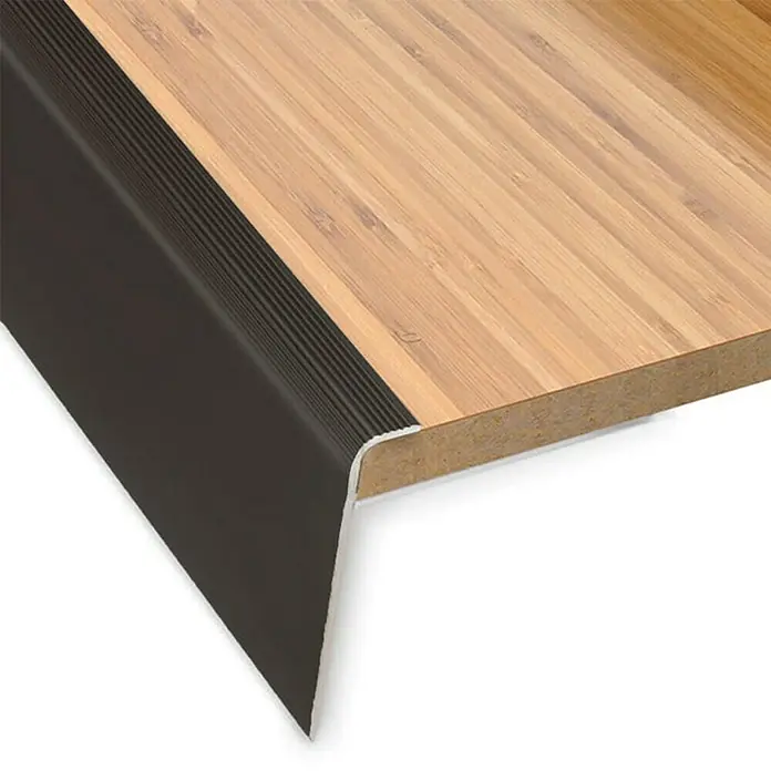 Floordirekt Treppenkantenprofil Safety 90 cm Bronze Hell - Aluminium, Bronze Dunkel, 90 x 5,3 cm, Eloxiert - Nahaufnahme einer Treppenkante aus Holz mit einem schwarzen, geriffelten Kantenschutz, der für zusätzliche Sicherheit sorgt.