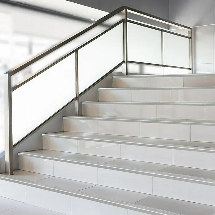 Floordirekt Treppenkantenprofil Safety 90 cm Silber - Aluminium, Silber, Eloxiert - Elegante Treppe mit Fliesenstufen und einem modernen Geländer mit satinierten Glaselementen, das dem Raum ein helles und stilvolles Ambiente verleiht.