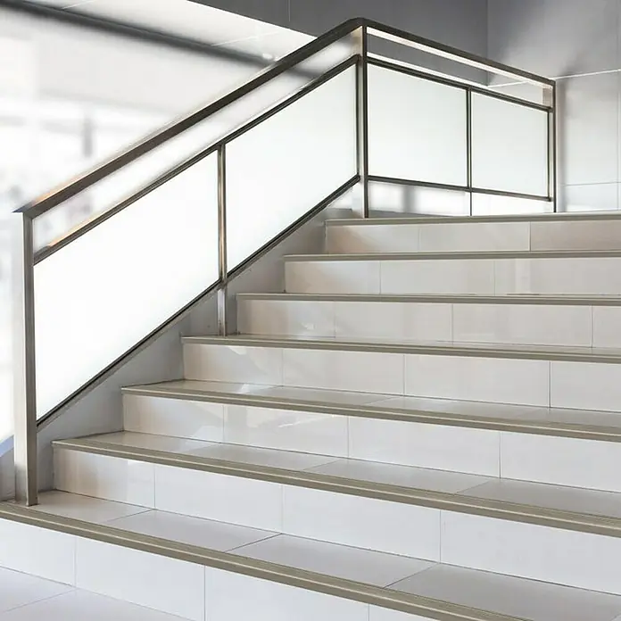 Floordirekt Treppenkantenprofil Safety 134 cm Bronze Hell - Aluminium, Bronze Dunkel, Eloxiert - Aufnahme von Innentreppen mit weißen Fliesen und einer modernen Treppe mit Metallgeländer. Der Fokus liegt auf dem Treppendesign.