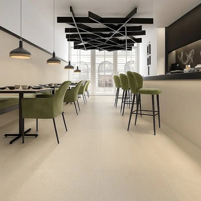 Pavimento porcelánico Balance - 90 x 90 cm, Arena, Mate - Elegante restaurante con sillas de terciopelo verde e iluminación moderna, creando un ambiente elegante y acogedor.