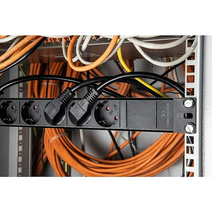as-schwabe Steckdosenleiste - 8-fach, Schwarz, Kabellänge: 3 m, IP20, Ohne Schalter - Nahaufnahme einer Stromleiste mit eingesteckten schwarzen Stromkabeln in einem Rack, umgeben von orangefarbenen Netzwerkkabeln.