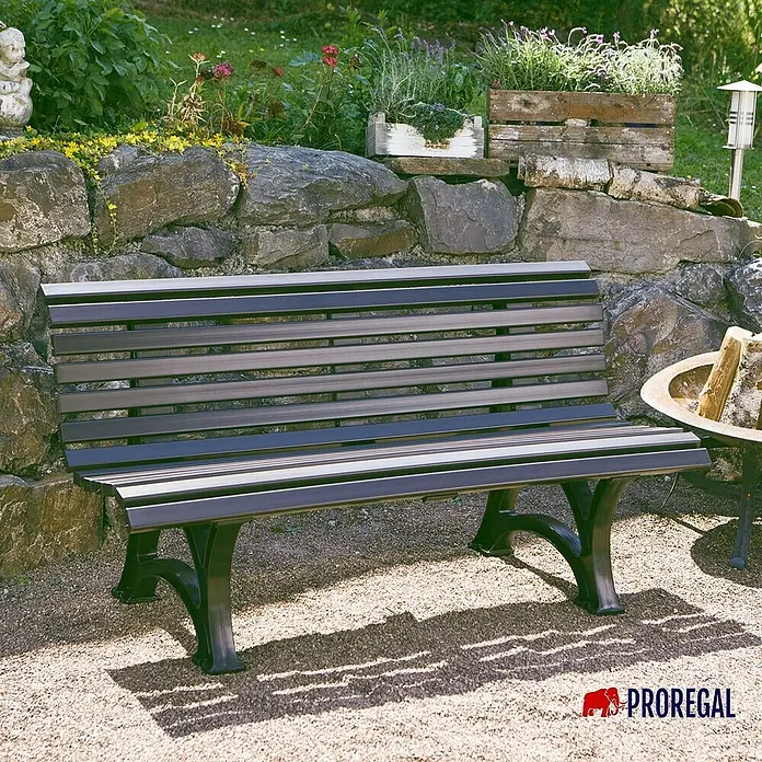 Proregal Gartenbank Jamaika 3-Sitzer aus Kunststoff - Graphitgrau - Eine stilvolle Gartenbank mit Lattenrost und geschwungenen Beinen vor einer Steinmauer mit Bepflanzung. Die Bank lädt zum Verweilen ein.