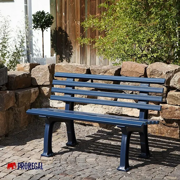 Proregal Gartenbank Antigua 2-Sitzer aus Kunststoff - Blau - Blaue Parkbank aus Metall vor einer Steinmauer. Ideal für Gärten und Parks, robust und stilvoll.